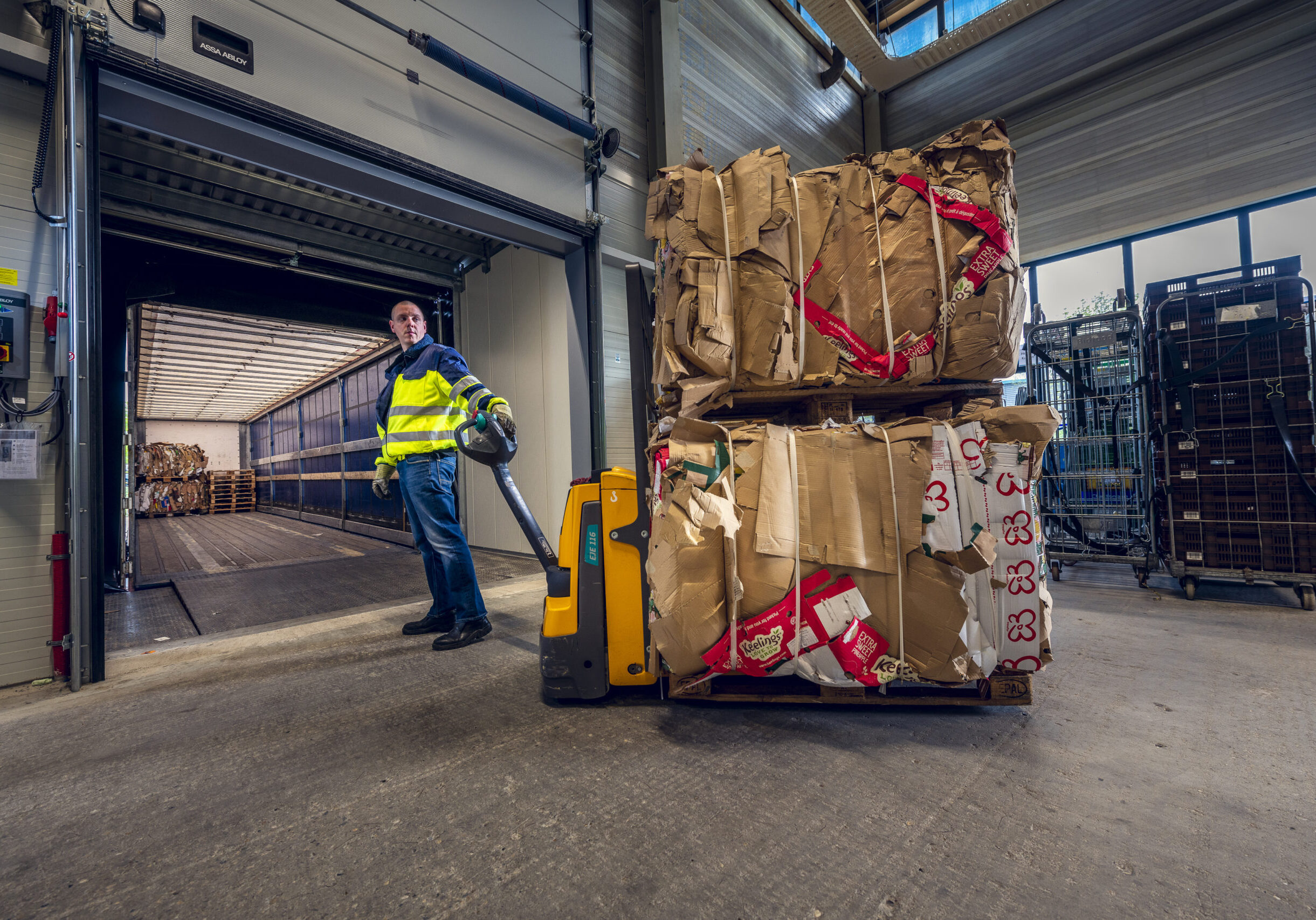 Geperste balen papier op een Europallet bij Schenk Recycling.